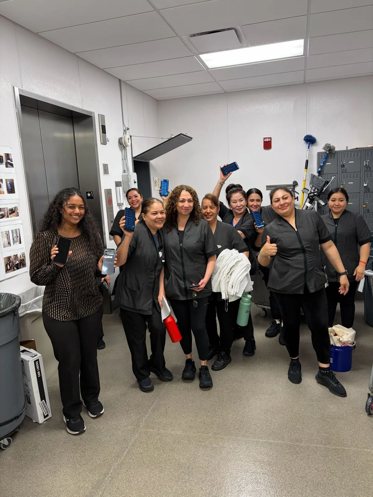 A hotel housekeeping team holding up phones running Lance