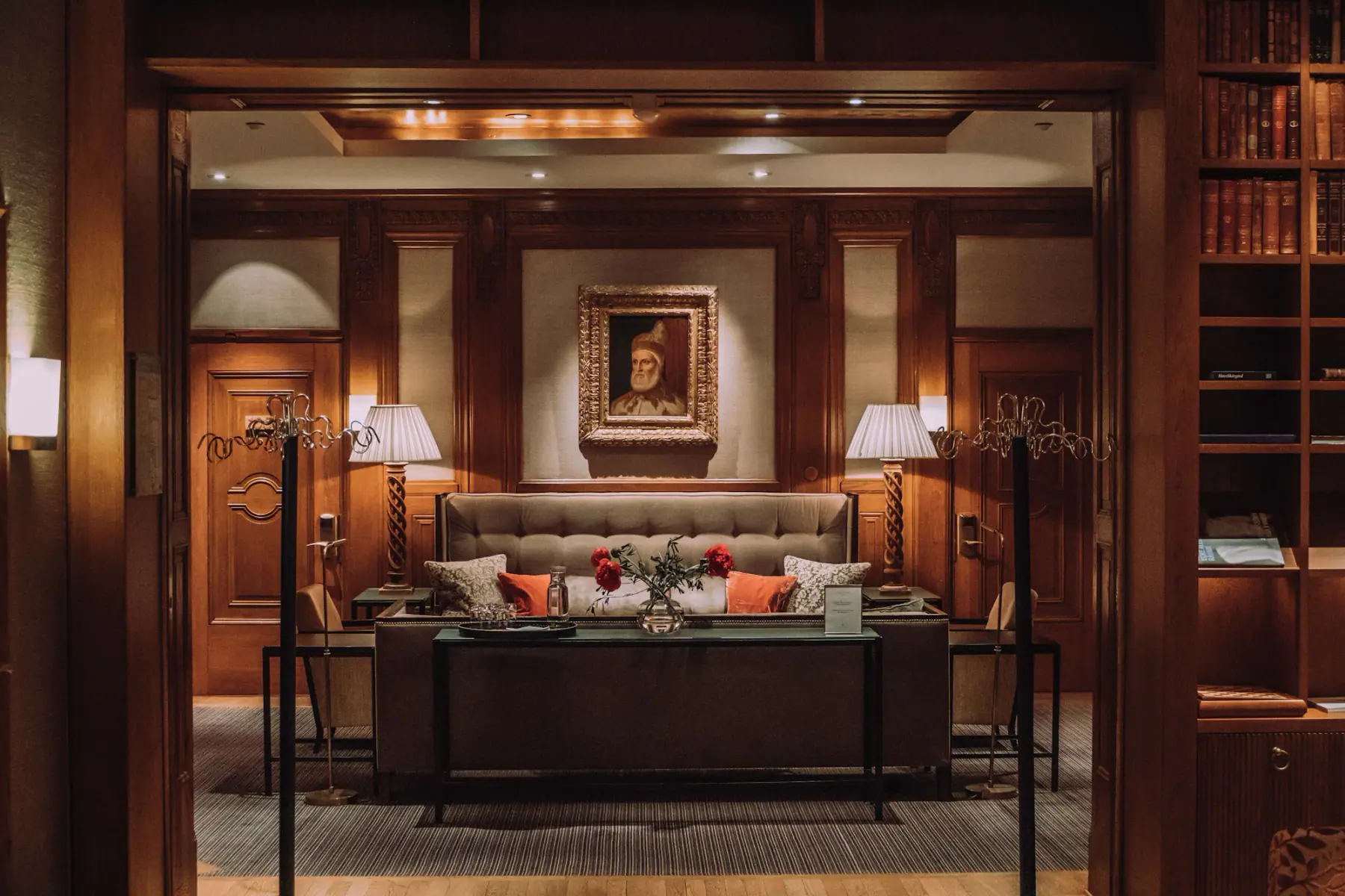 A wood-panelled hotel suite: a sofa between two lamps beneath a framed portrait